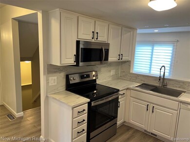 Kitchen with stainless steel appliances, white cabinetry, light wood-type flooring, decorative backsplash, and recessed lighting