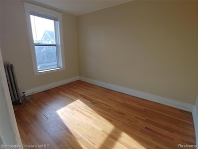 Empty room with wood-type flooring and radiator heating unit