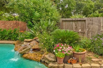 Lush landscaping surrounds the sparkling pool and