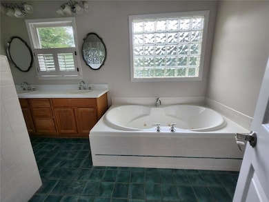 Bathroom featuring a whirlpool tub, tile patterned floors, and double vanity