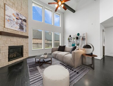 This inviting and bright living room features recessed lighting, a high ceilings, ceiling fan, beautiful dark stained wood floors, elegant fireplace, and large wall of windows allowing wonderful natural light!