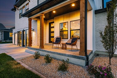 Exterior entry at dusk featuring covered porch, brick siding, and board and batten siding