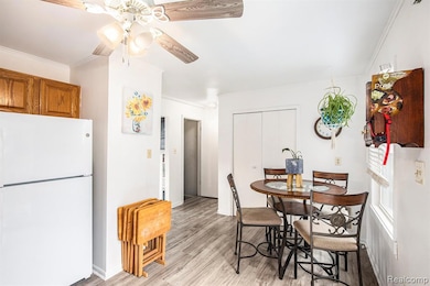 Dining area with ornamental molding, light wood-style floors, and ceiling fan