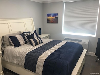 Bedroom with a wall mounted air conditioner, crown molding, and dark tile patterned flooring