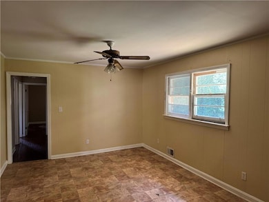 Unfurnished room featuring ornamental molding, a ceiling fan, and stone finish flooring