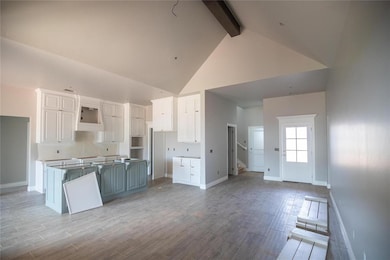 Kitchen with high vaulted ceiling, beam ceiling, custom exhaust hood, a kitchen island, and white cabinets