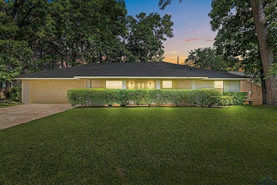 Ranch-style home featuring an attached garage, a front yard, driveway, and brick siding