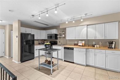 Kitchen with light countertops, white cabinetry, appliances with stainless steel finishes, open shelves, and light tile patterned flooring