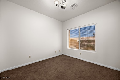 Empty room with dark carpet, visible vents, basebo
