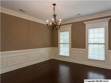 Separate dining room with hardwood floors, heavy trimwork and wainscoting.
