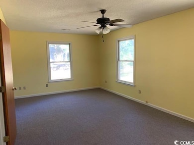 Empty room featuring dark colored carpet, a textured ceiling, and ceiling fan