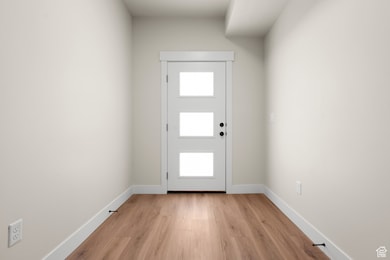 Doorway to outside with wood finished floors and baseboards