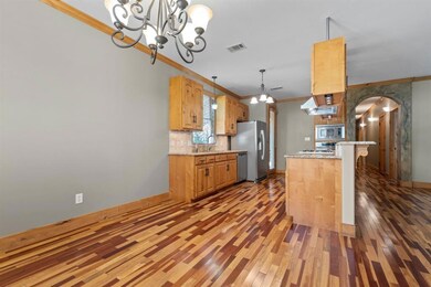 Kitchen with light stone countertops, pendant lighting, a chandelier, decorative backsplash, and ornamental molding