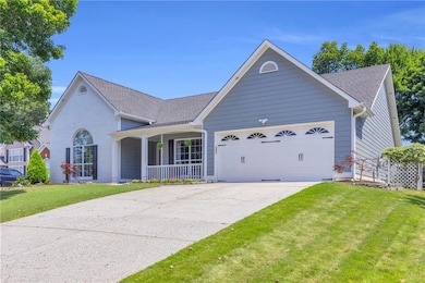 View of front of property with an attached garage, a front yard, roof with shingles, covered porch, and driveway