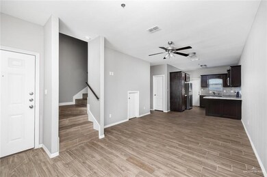 Kitchen featuring light countertops, light wood-style floors, open floor plan, dark brown cabinets, and freestanding refrigerator