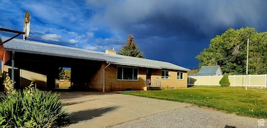 Ranch-style home featuring concrete driveway, brick siding, a chimney, and an attached carport
