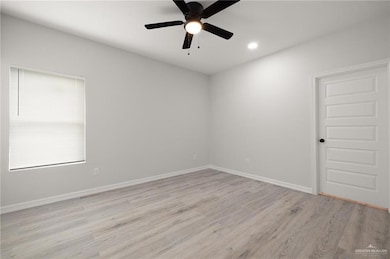 Unfurnished room featuring light wood-style floors, ceiling fan, baseboards, and recessed lighting