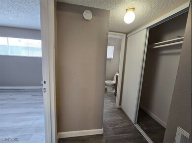 Corridor with a textured ceiling, wood finished fl