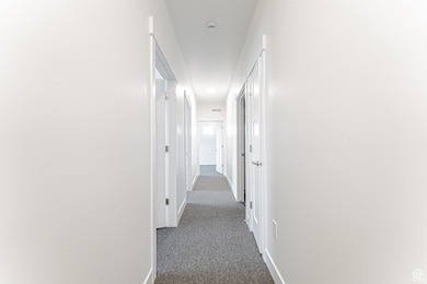Hall featuring dark carpet and baseboards