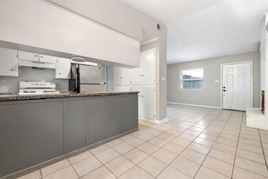 Kitchen featuring white cabinets, freestanding refrigerator, light tile patterned flooring, range, and backsplash