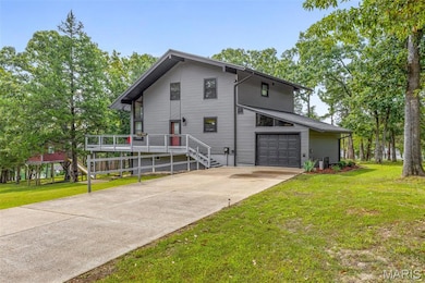 View of side of home featuring a yard, concrete driveway, an attached garage, and stairs