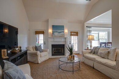 The Gas Fireplace is the Focal Point of the Living Room! It's Perfectly Balanced with Doors to the Screened Porch on Each Side! Designer Sconces, Rattan Blinds, a Vaulted Ceiling, and Neutral Paint are Beautiful in this Space! 