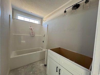 Bathroom featuring a textured ceiling, concrete fl