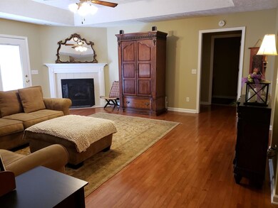 The spacious living room features tray ceiling, gleaming hardwood Floors, a fireplace, and more