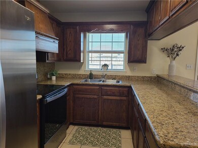 Kitchen featuring freestanding refrigerator, range with electric stovetop, light tile patterned flooring, and dark brown cabinets