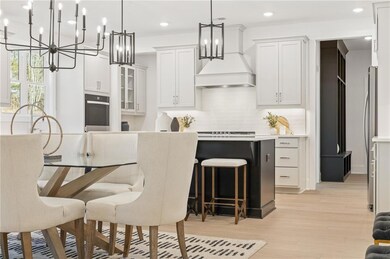 Kitchen with tasteful backsplash, a chandelier, light countertops, premium range hood, and oven