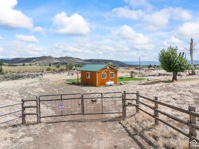 View of yard featuring a gate, a rural view, a mountain view, and an outbuilding