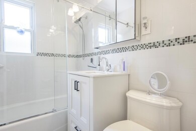 Bathroom with bath / shower combo with glass door, tile walls, and vanity