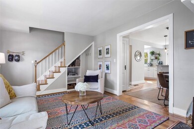 View into the living room with stairs to the second floor and view into the kitchen (showing the hall closet for coat storage on immediate left in the kitchen).