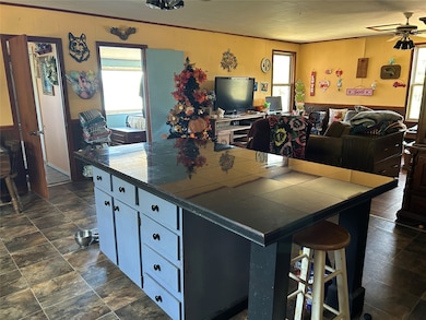 Kitchen featuring open floor plan, healthy amount of natural light, a breakfast bar area, and ceiling fan