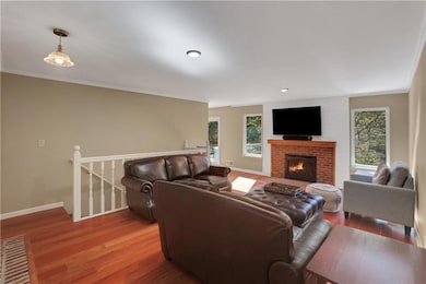 Living area with wood finished floors, a brick fireplace, and ornamental molding
