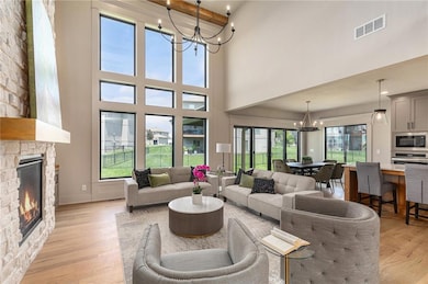 Living area featuring a chandelier, a fireplace, a high ceiling, and light wood-style flooring