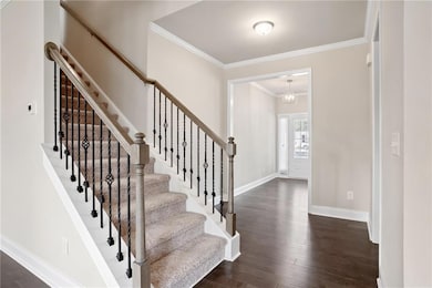 Staircase featuring crown molding, wood finished floors, and a chandelier