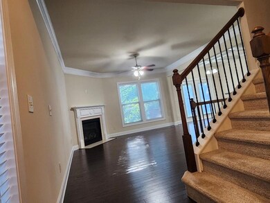 Unfurnished living room featuring ornamental molding, a ceiling fan, a high end fireplace, dark wood-style flooring, and stairway