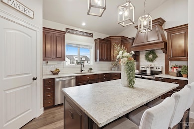 Kitchen featuring appliances with stainless steel finishes, a kitchen breakfast bar, light wood-type flooring, custom exhaust hood, and tasteful backsplash