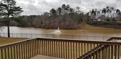 Wooden deck with a water view, fence, and a lawn