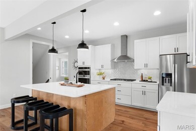 Kitchen with decorative backsplash, light wood-style flooring, an island with sink, white cabinetry, and recessed lighting