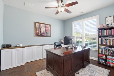 Home office with dark wood-style floors and a ceiling fan