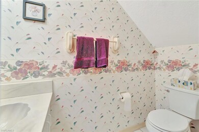Bathroom featuring lofted ceiling, wallpapered walls, and a textured ceiling