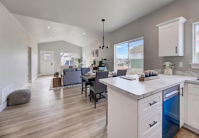 Kitchen with lofted ceiling, white cabinetry, light countertops, open floor plan, and a peninsula