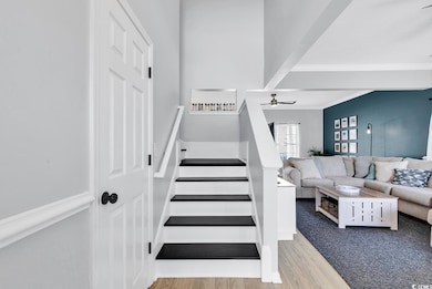 Stairs with crown molding, wood finished floors, a