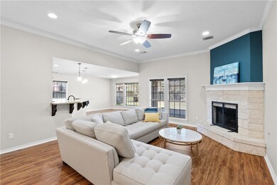 Living room with plenty of natural light, ornamental molding, wood finished floors, recessed lighting, and a stone fireplace