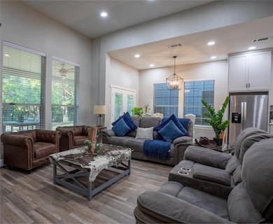 Living area featuring recessed lighting, wood finished floors, a chandelier, and french doors