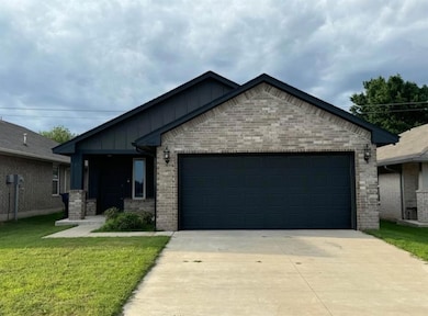 Ranch-style house with board and batten siding, an attached garage, concrete driveway, a front lawn, and brick siding