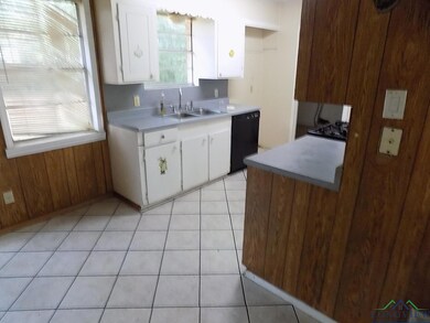 Kitchen featuring wood walls, sink, light tile pat
