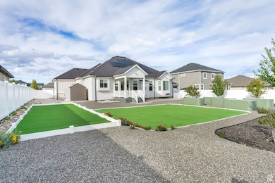 Rear view of house with roof mounted solar panels, a fenced backyard, and a patio